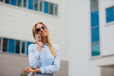 Portre genç işkadını cam duvara yaslanmış iken cep telefonuyla iletişim