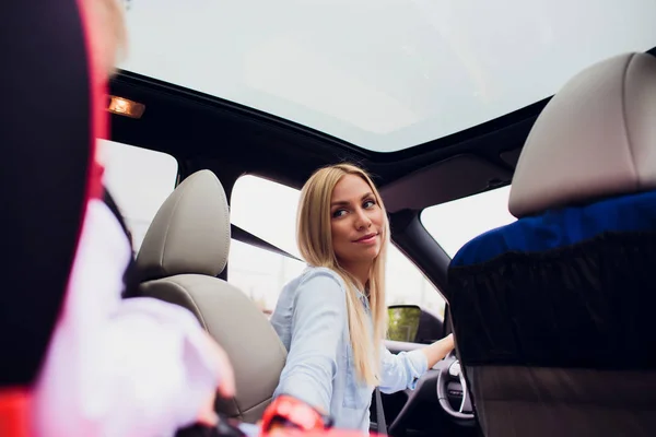 Close-up shot mother driving car, buckled seat belt. Son on back seat. Family holding their thumbs up