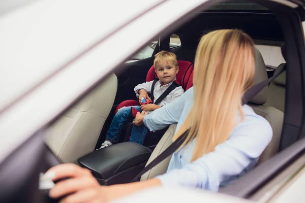 Gros plan mère voiture de conduite, ceinture de sécurité bouclée. Fils sur le siège arrière. Famille tenant le pouce levé — Photo