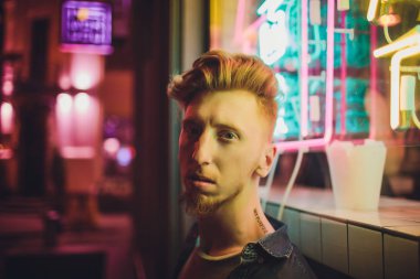 Siyah gece arka plan üzerinde genç kırmızı saçlı adam. gece şehrin ışıkları. model üzerinde ışık açık hava reklam düşüyor.