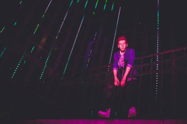 Siyah gece arka plan üzerinde genç kırmızı saçlı adam. gece şehrin ışıkları. model üzerinde ışık açık hava reklam düşüyor.