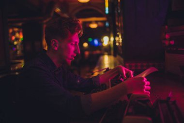 Genç Eski daktilo yazmak adam. karanlık aydınlatma, Restoran, modern giysiler, eski yazar alışkanlıkları