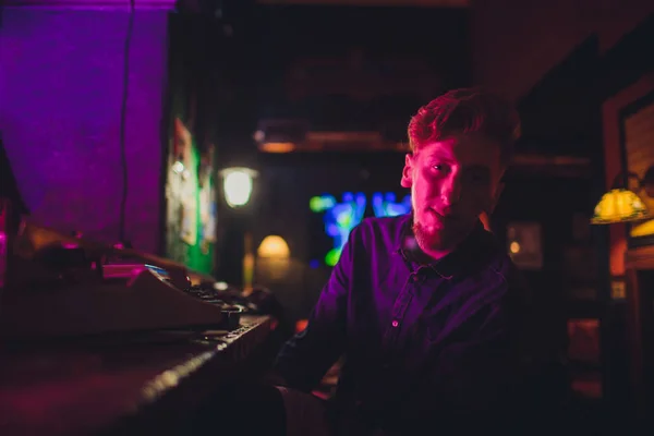Un jeune homme écrit sur une vieille machine à écrire. dans l'obscurité, restaurant, vêtements modernes, vieilles habitudes d'écrivain — Photo