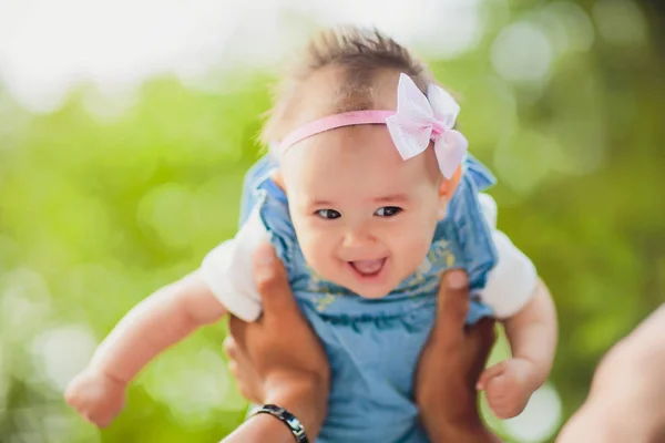 Щасливий молодий чоловік тримає усміхнену 2-4-місячну дитину на фоні листя не в фокусі — стокове фото