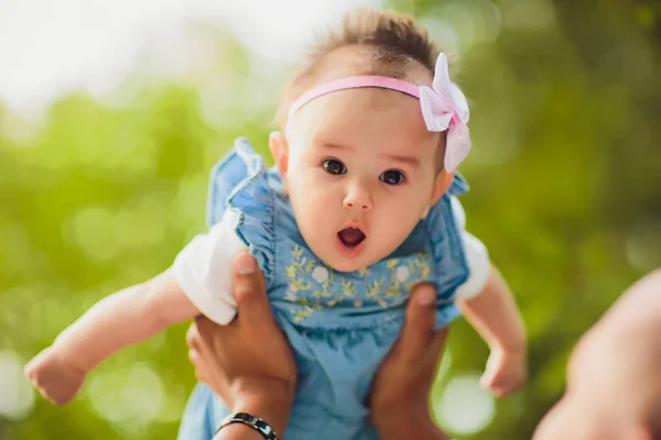 Szczęśliwy młody człowiek posiadający uśmiechający się 2-4 miesiące życia dziecka na tle liści nie w centrum uwagi — Zdjęcie stockowe