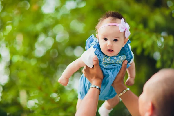 Gelukkig jonge man houden een lachende 2-4 maanden oude baby op een achtergrond van bladeren niet in focus — Stockfoto