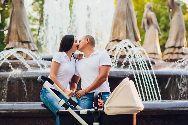 Echtpaar zittend op de rand van de stad fontein, baby in kinderwagen, concept van de liefde — Stockfoto