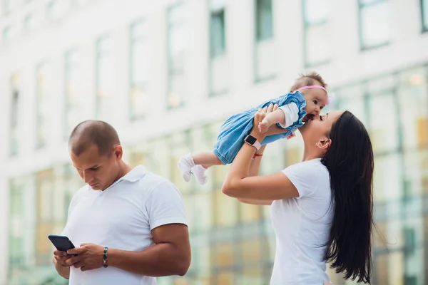 Vrouw kind houdt, mens is permanent en het gebruik van de smartphone. familie concept — Stockfoto