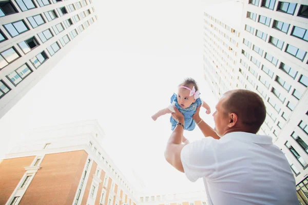 Vader heeft zijn dochter op de achtergrond de wolkenkrabbers. glazen gebouwen. kind op de hemelachtergrond — Stockfoto