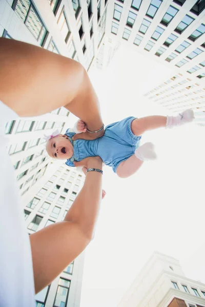 Padre sostiene a su hija en rascacielos de fondo. edificios de vidrio. niño en el cielo fondo — Foto de Stock