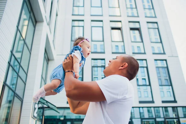 Gelukkig jongeman een lachende 2-4 maanden oude baby te houden tegen de achtergrond van de ingang van het huis. glazen gebouw — Stockfoto