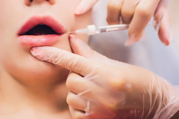 Young Woman Gets an Injection in her Lips in Beauty salon. Beauty Injections -Woman lying in the beautician office. Increase Lips by Hyaluronic acid, Contouring procedure, revitalization