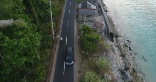 Uomo in sella a una moto con tavola da surf su strada vicino a bellissime terrazze di riso, cultura dell'attività indonesiana. Un bell'uomo andra 'a fare surf spot. Surf stile di vita avventura — Video Stock