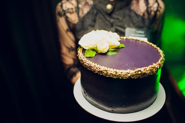 Жінка тримає фіолетовий торт на чорному тлі . — стокове фото