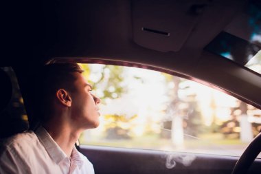 Yan genç adam bir kentsel sokağa arabasını kullanıyor gibi bir e-sigara sigara üzerinden görüntülemek