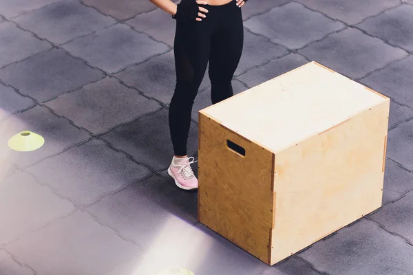 Mujer atlética se para en una caja de madera en un club de gimnasia . —  Fotos de Stock