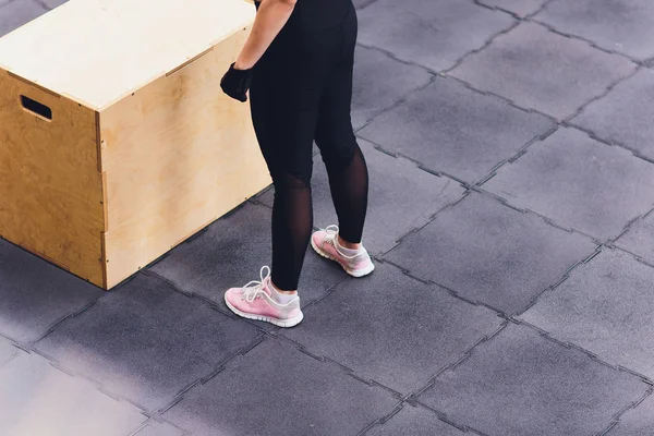 Atletisk kvinna står på en trälåda i en gym-klubb. — Stockfoto