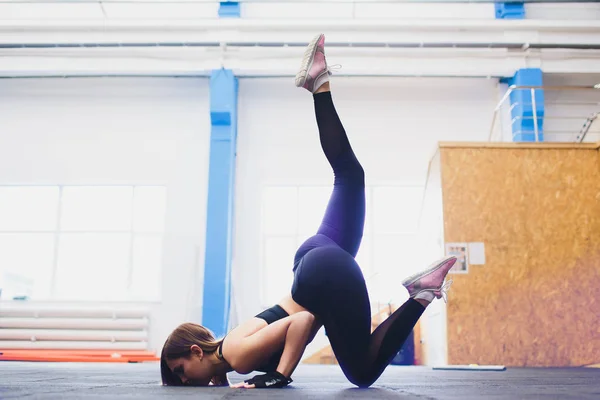 Vista dall'alto di una ragazza in forma e sportiva che fa esercizi di stretching per le gambe. Giovane donna magra che fa spago in palestra, allo stadio. Interni . — Foto Stock