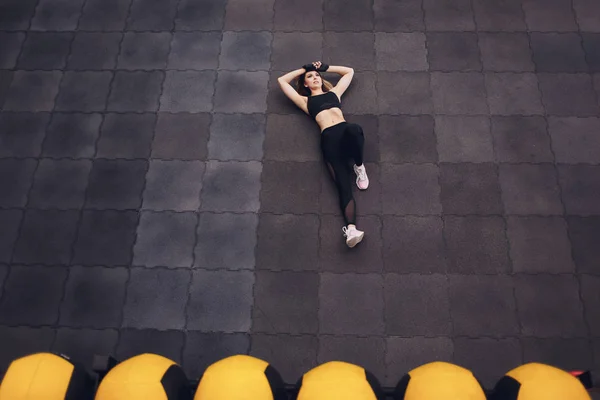 Vista superior de una chica en forma y deportivo haciendo ejercicios streching para las piernas. Joven mujer delgada haciendo twine en el gimnasio, estadio. En interiores . — Foto de Stock