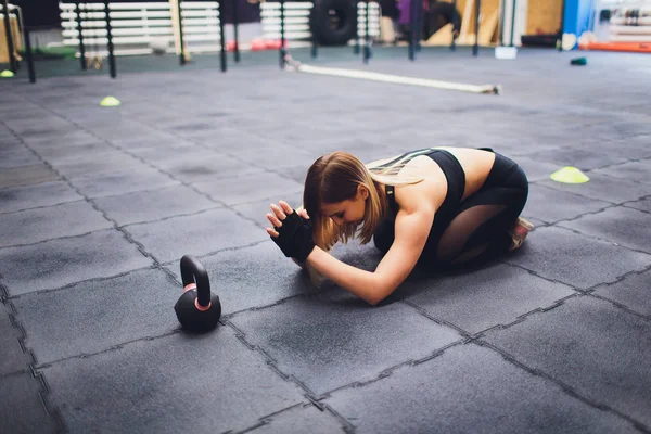 Jonge sportieve vrouw die zich uitstrekt benen in de sportschool. — Stockfoto