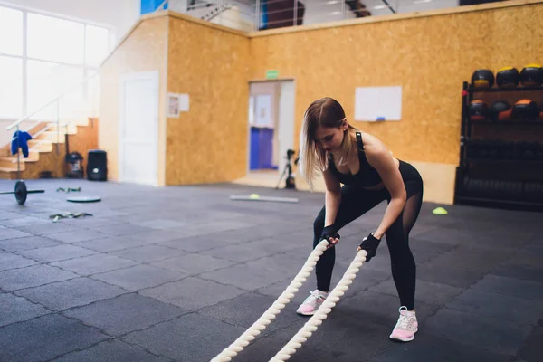 Silna kobieta ćwiczenia z bitwy liny na siłowni. Sportowiec bitwy liny treningu w siłowni. — Zdjęcie stockowe