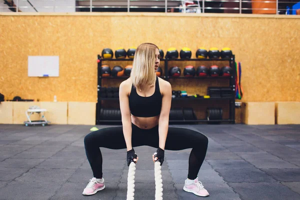 Сильна жінка тренується з бойовими мотузками у спортзалі. Спортсмен робить тренування на мотузці в спортзалі . — стокове фото