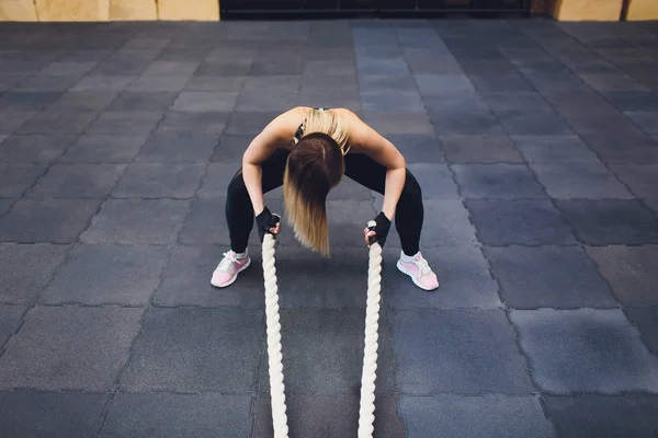 Strong woman exercising with battle ropes at the gym. Athlete doing battle rope workout at gym. woman tired to train