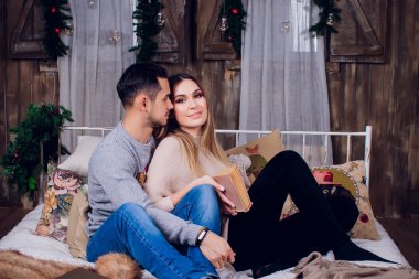 Evde güzel vakit. Güzel genç sevgi dolu çift bağ birbirlerine ve gülümseyen bir kitap kadın.