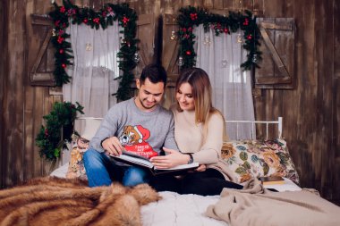 Evde güzel vakit. Güzel genç sevgi dolu çift bağ birbirlerine ve gülümseyen bir kitap kadın.