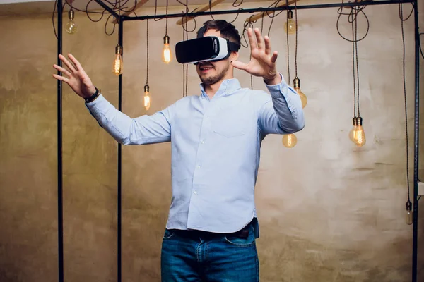 Amazed man looking in a VR goggles and gesturing.