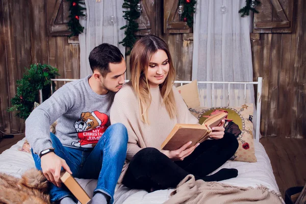 Δαπάνες ωραία στιγμή στο σπίτι. Όμορφη νεαρή αγάπη ζευγάρι συγκόλληση μεταξύ τους και να χαμογελούν ενώ γυναίκα κρατά ένα βιβλίο. — Φωτογραφία Αρχείου