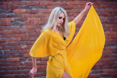 bir tuğla duvar arka plan sarı elbiseli güzel kız yakın çekim