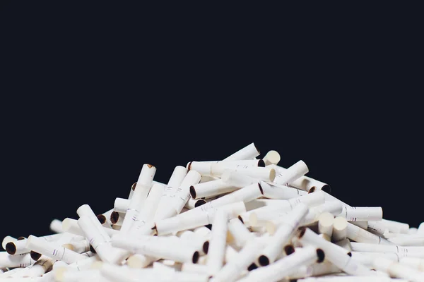 Cigarros eletrônicos mais recentes, sistema de aquecimento de tabaco IQOS, tabagismo, azul escuro isolado em fundo preto. montanha de cigarros usados, paus — Fotografia de Stock