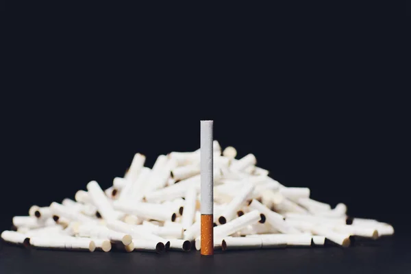 Cigarros eletrônicos mais recentes, sistema de aquecimento de tabaco IQOS, tabagismo, azul escuro isolado em fundo preto. montanha de cigarros usados, cola cigarro clássico no fundo de novos paus — Fotografia de Stock