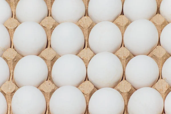 Several white eggs in an egg carton.