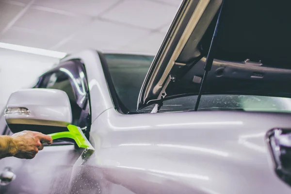 Spezialist für Autofolien legt Vinylfolie oder -folie mit Tonschaber auf Autoscheiben — Stockfoto