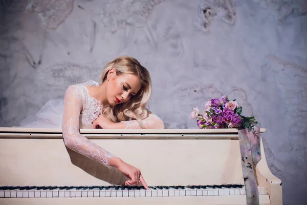 Krása Blondýna žena portrét. Krásná nevěsta s dlouhé kudrnaté blond vlasy sedí u klavíru. Bílé vlasy. Perfektní pleť a Make-upu. Prodlužování vlasů. — Stock fotografie