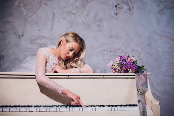 Bellezza Bionda Ritratto Donna. Bella sposa con lunghi capelli biondi ricci seduta al pianoforte. Capelli bianchi. Pelle e trucco perfetti. Estensioni dei capelli . — Foto Stock