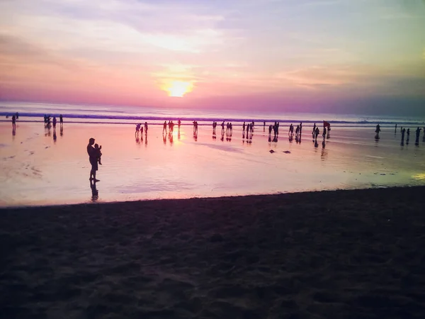 Pessoas no pôr do sol fundo na praia arenosa — Fotografia de Stock