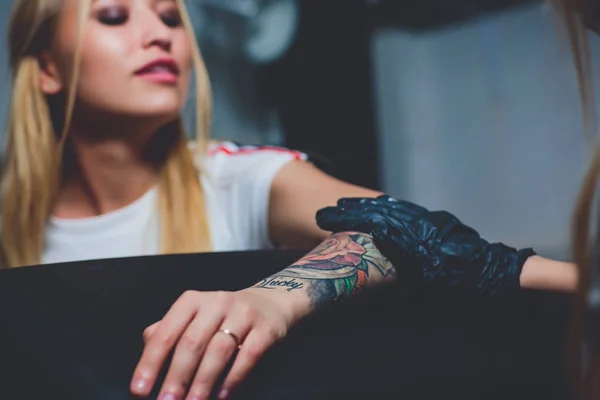 Dívka tattoo umělec dělá tetování na rukou, růžovou psací stroj, na černý stůl. — Stock fotografie