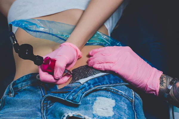 タトゥー アーティスト、彼女の腹、ピンクのタイプライターに入れ墨、ピンクの手袋、白い背景のスペシャ リスト. — ストック写真