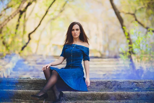 Красива молода жінка в блакитній сукні позує перед камерою на фоні природи в лісі . — стокове фото