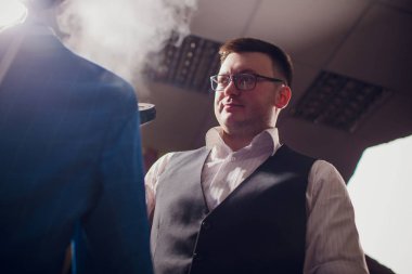 terzi keser ve bir takım elbise diker. Terzilik dükkanı genç bir erkekte erkek giyim yapar. Ismarlama giyim Atölyesi. onun elinde Elektrikli Ütü tutar. ıslak-ısıl işlem