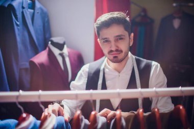 Omuz üzerinden görünümü sakallı moda tasarımcısının uygun takım elbise modeli, ateş yakın çekim için ısmarlama.