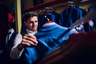 Terzi, terzilik. Erkek takım elbise, terzi atölyesinde. Elegant satırda asılı takım elbise mans. Lüks erkek klasik zarif mens butik rafa uygun.
