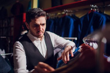 Terzi, terzilik. Erkek takım elbise, terzi atölyesinde. Elegant satırda asılı takım elbise mans. Lüks erkek klasik zarif mens butik rafa uygun.