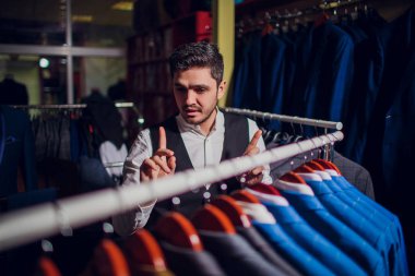 Terzi, terzilik. Erkek takım elbise, terzi atölyesinde. Elegant satırda asılı takım elbise mans. Lüks erkek klasik zarif mens butik rafa uygun.