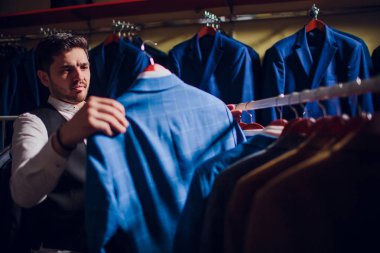 Terzi, terzilik. Erkek takım elbise, terzi atölyesinde. Elegant satırda asılı takım elbise mans. Lüks erkek klasik zarif mens butik rafa uygun.