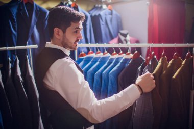 Terzi, terzilik. Erkek takım elbise, terzi atölyesinde. Elegant satırda asılı takım elbise mans. Lüks erkek klasik zarif mens butik rafa uygun.