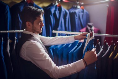 Terzi, terzilik. Erkek takım elbise, terzi atölyesinde. Elegant satırda asılı takım elbise mans. Lüks erkek klasik zarif mens butik rafa uygun.